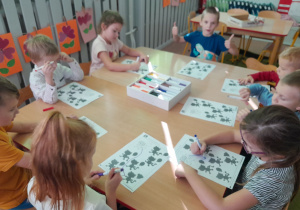 Dzieci z grupy 5-6 latków siedzą przy stolikach uzupełniają kartę pracy