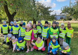 Dzieci na spacerze w sadzie pozują wśród jabłoni - kolejne ujęcie.