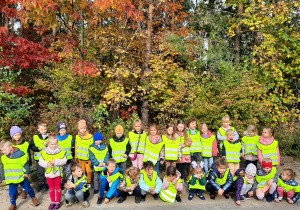 Dzieci na spacerze w lesie. Pozują na tle drzew w jesiennych kolorach - kolejne ujęcie.