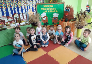 Dzieci na tle dekoracji związanej z Dniem Ziemniaka.