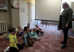 Dzieci słuchają opowiadania pani bibliotekarki o polskich wynalazcach.