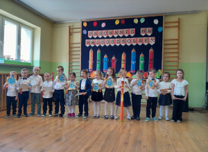 Dzieci z grupy 5-6 latków na tle dekoracji z dyplomami