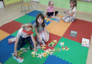 Dziewczynki na dywanie układają puzzle.
