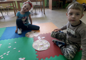 Dzieci na dywanie prezentują pracę plastyczną: "Pizza".