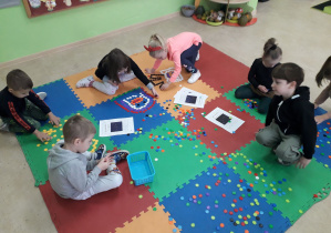Dzieci na dywanie konstruują z klocków gwiazdozbiory.