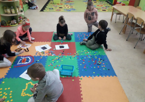 Dzieci na dywanie konstruują z klocków gwiazdozbiory.