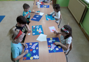 Dzieci przy stolikach wykonują pracę plastyczną "Kosmos".