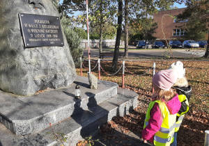Dwie dziewczynki stoją przed wartkowickim obeliskiem upamiętniającym poległych w walce o Ojczyznę.