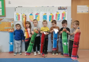 Dzieci trzymają papierowe kolorowe kredki