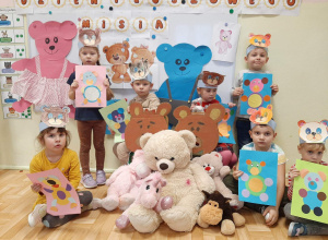 Dzieci z grupy 3,4,5 latków pozują na tle dekoracji z okazji dnia pluszowego misia ze swoimi misiami maskotkami, prezentują też wykonane prace plastyczne.