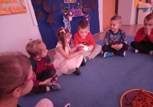 Dzieci siedzą i podają sobie magiczny płomień