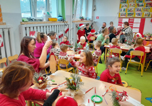 Dzieci i rodzice podczas warsztatów świątecznych wykonują stroiki i ozdoby świąteczne