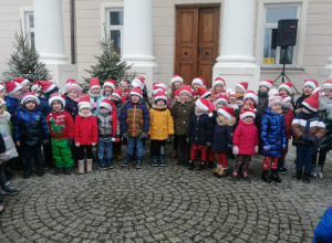 Grupa przedszkolaków w świątecznych strojach stoi na tle pałacu w parku w Starym Gostkowie.