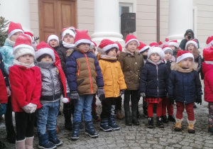 Dzieci stoją na placu przed pałacem i śpiewają