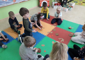 Dzieci na dywanie składają renifera z części.