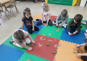 Dzieci na dywanie składają renifera z części.