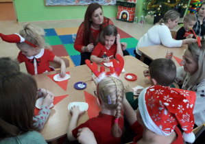 Dzieci wspólnie z rodzicami wykonują papierowego Mikołaja.