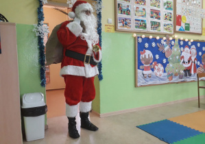 Święty Mikołaj odwiedza dzieci w sali.