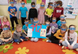 Dzieci pozują do zdjęcia z w granatowych maskach Fast Heroes, trzymają w rękach plakat z numerem alarmowym 112