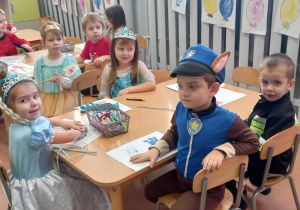 Dzieci kolorują obrazki przy stolikach
