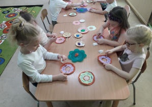 Dzieci przy stolikach dekorują "papierowego" pączka.