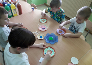 Dzieci przy stolikach dekorują "papierowego" pączka.