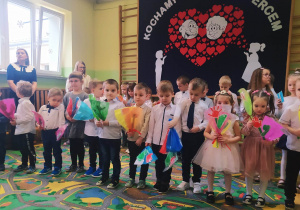 Dzieci stoją i trzymają prezenty na tle dekoracji przedszkolnej