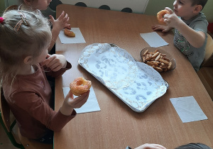 Dzieci z grupy 3,4,5 latków degustują tłustoczwartkowe przysmaki przy stoliku.