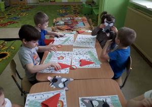 Dzieci przy stolikach wykonują pracę plastyczną "Las Czerwonego Kapturka."