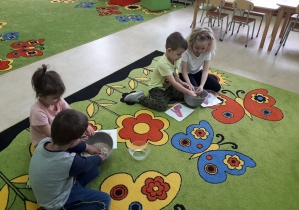 Dzieci na dywanie bawią się w Kopciuszka, oddzielają ziarenka grochu od kaszy.