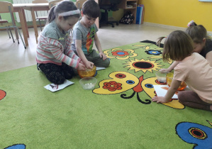 Dzieci na dywanie bawią się w Kopciuszka, oddzielają ziarenka grochu od kaszy.