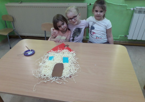 Dziewczynki prezentują słomiany domek z baśni "Trzy świnki".