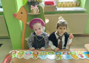 Dziewczynki przebrane w kostiumy francuskie układają puzzle.