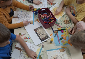 Dzieci siedzące przy stoliku malują obraz inspirowany dziełem Gustawa Klimta.