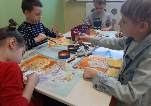 Dzieci siedzące przy stoliku malują obraz inspirowany dziełem Gustawa Klimta, inne ujęcie.