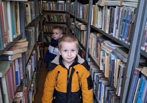 Chłopcy stoją wśród regałów z książkami