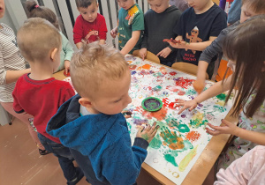 Dzieci malują obraz grupowy używając różnych narzędzi