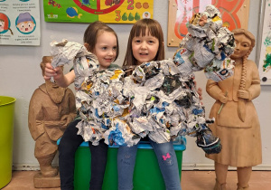 Dziewczynki trzymają przedszkolną rzeźbę z gazet