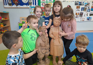 Dzieci stoją z rzeźbami z drewna