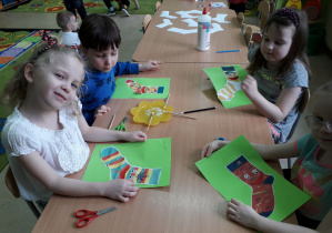 Dzieci przy stolikach prezentują prace plastyczną "Skarpetka".