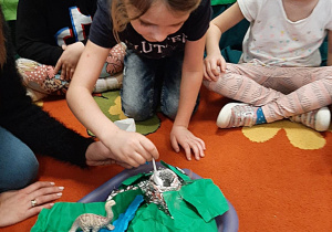 Dzieci siedzą na dywanie, wykonują doświadczenie - wulkan z octu i sody, inne ujęcie ujęcie.