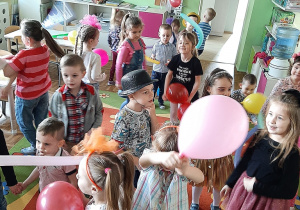 Dzieci tańczą w przedszkolnej sali trzymając lub podbijając kolorowe balony - kolejne ujęcie.