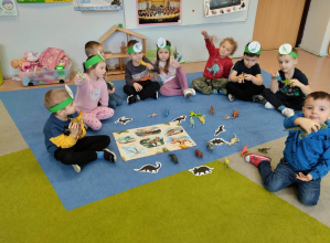 Przedszkolaki na dywanie podczas zabawy z dinozaurami