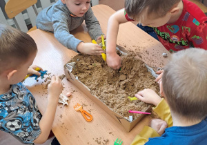Dzieci szukają kości dinozaurów ukrytych w piasku