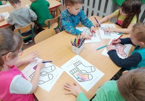 Dzieci kolorują przy stolikach skarpety