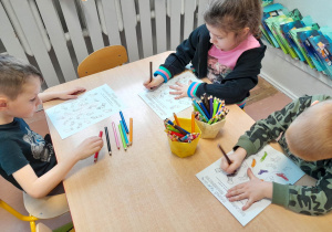 Dzieci kolorują przy stolikach skarpety