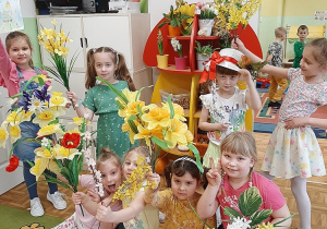 Grupa dziewczynek pozuje do fotografii trzymając w dłoniach wiosenne kwiaty.