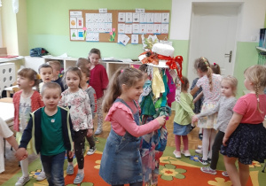 Dzieci tańczą w kole. Dziewczynka w środku koła trzyma Marzannę.