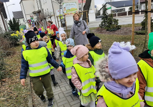 Dzieci przed budynkiem przedszkola, ustawione w parach przygotowują się do wiosennego pochodu.