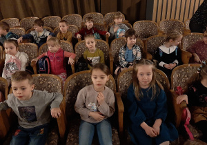 Dzieci siedzą na widowni w sali teatralnej - następne ujęcie.